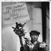 Charlie Jackson, picketing with Sheriff's officers, proudly displaying Junior Deputy Sheriff card