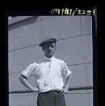 Young man posed in front of the wall of a granite building