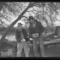 Shows man pouring large bottle of Four Roses into mug held by another man