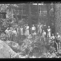 Thirteen people standing in front of a cabin