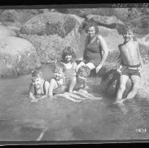 Children and adults playing and swimming in a river