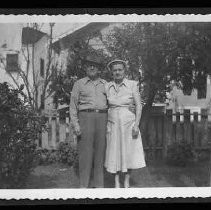 A man and woman standing next to fence