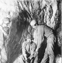 Three miners drilling a hole