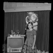 Girl standing next to a television set