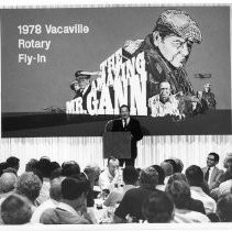 Ernest K. Gann, author stands before poster at the Rotary Fly-In at the Nut Tree Airport in Vacaville, California