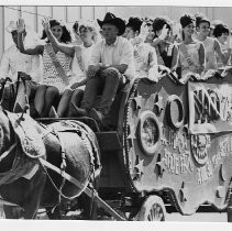 View of a parade down K Street in Sacramento for the California State Fair in 1966 showing a horse-drawn wagon with the "Maids of California" aboard