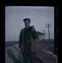 Man standing along side railroad tracks holding a bag