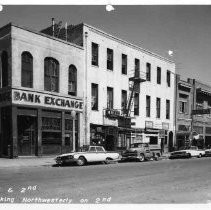 The Bank Exchange building, OK Cafe, Olympia Grill, Phil's Barber Shop, and the Channel Restaurant appear in the image. The Bank Exchange building, OK Cafe, Olympia Grill, Phil's Barber Shop, and the Channel Restaurant appear in the image