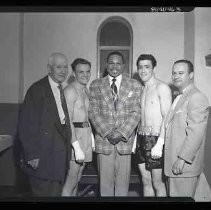 Two boxers standing with three men in suits