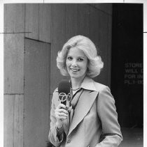 Joan Lunden, standing and holding a microphone