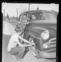 Boy changing a tire on a car