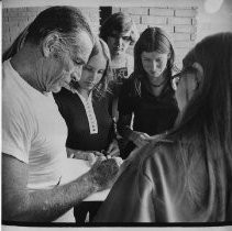 Buster Crabbe famous for his film roles as Tarzan and Flash Gordon. He earned a gold medal in swimming in the 1932 Olympic Games. Here he is signing autographs