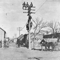 Men Atop Power Pole