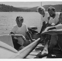 Bob Grind in a small motor board, with three friends on dock