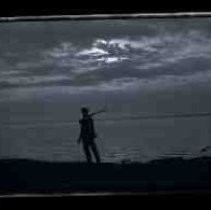 A young man walking along the edge of a lake