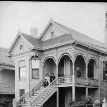 Unidentified house with four people sitting on porch