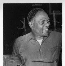 Retired boxer Lloyd Marshall holding an award plaque