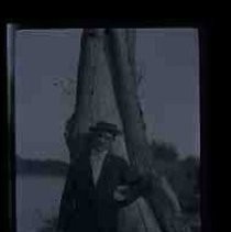 An young man standing in front of a large tree