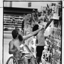 Gene Howard, a wheelchair athlete who competed in marathons, played tennis, and taught sports to handicapped children. He is shown shopping in a supermarket with his son Eric