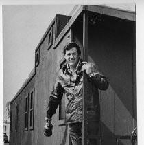 Ron Gilliland. Caption reads, "Builder Gilliland dwarfs the State Capitol, above, and stands outside the caboose he built to houe the model train exhibit, below."