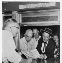 Frank S. Christy receiving the first sheet of Pony Express stamps from postal worker, Thaine Nelson