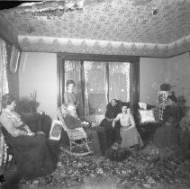 Interior view of seven men and women sitting in a parlor