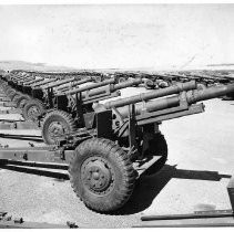 Two long rows of howitzers are lined in military precision near the bay at the Benicia Arsenal