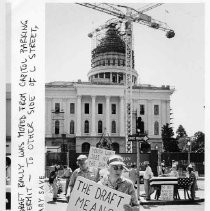 Demonstrators with signs protest the proposed military draft near the California State Capitol