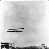 Copy print from a 1910 image of an aviator, Charles K. Hamilton racing his airplane at the old State Fair Ground