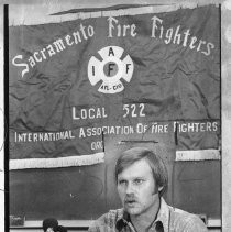 Bob Kern, union leader, speaking at a microphone in front of a Sacramento Fire Fighters union banner