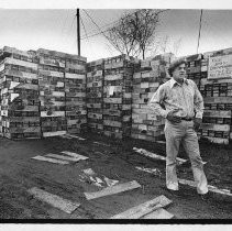Howard Gifford. Caption reads, "Howard Gifford of 494 Lampasas, Sacramento, stands in front of some 7000 Navy ammo boxes which are poisoned. He bought them from Eastman Building Supply Co. and has them stored in his backyard."