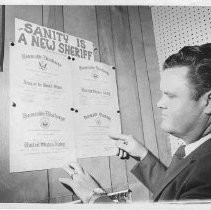 Duane Lowe, looking at Honorable Discharge papers tacked on wall