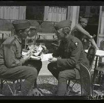 Two soldiers sitting at an outdoor cafe in France