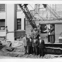 View of the Pioneer Telegraph Building at 1015 2nd Street in Old Sacramento. A group of unidentified men in business suits surround the construction equipment