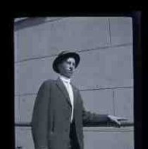 A young man wearing a suit leaning against a metal rail
