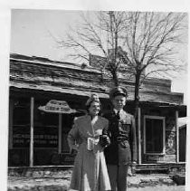 Photograph of unidentified man in military uniform and woman in front of "Billy the Kid Curio Shop."