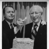 Cal-Western President Harold S. Hook (left) lights the candle on a birthday/retirement cake for H. Harold Leavey, right