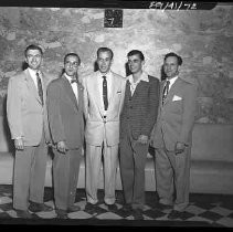 Five men posed in front of a wall