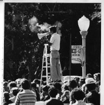 Robert T. (Bob) Matsui on a ladder with a megaphone during a race in River Park