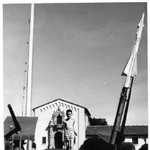 A salute gun by a flagpole and an Ajax missile frame the headquarters building of Benicia Arsenal. The youth running across the lawn is Stuart, son of Major Harold Labchansky of the military staff