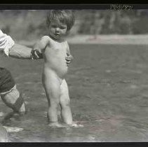 Naked baby standing in shallow water