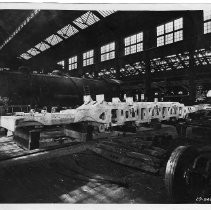 Interior view of the Southern Pacific Railroad Company's carbarn construction shops showing employees building and repairing railcars and locomotives