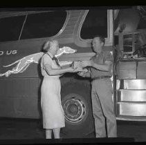 An undientified woman handing a bus driver a package