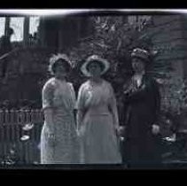 Three women standing in the front yard of a house