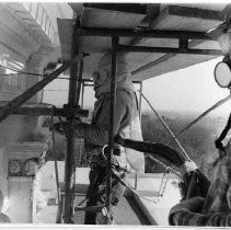 Standing on scaffolding high above the city, workers sandblast the side of the California State Capitol dome