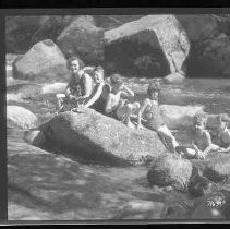 Children and adults playing and swimming in a river