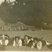 Girls with hats laying on riverbank