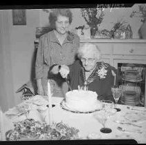 An elderly woman cutting a birthday cake