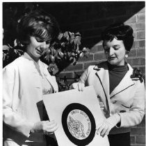 Camellia Princess, Lillian Abbott, left of Sacramento City College poses with Martha Sager Derr assistant general chairman of the Camellia Festival show off the new emblem