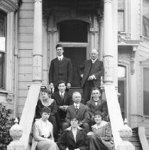 People seated on steps of a Victorian house